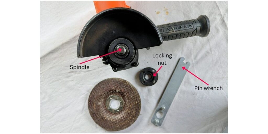 shows angle grinder, pin wrench, locking nut and cutting disc removed